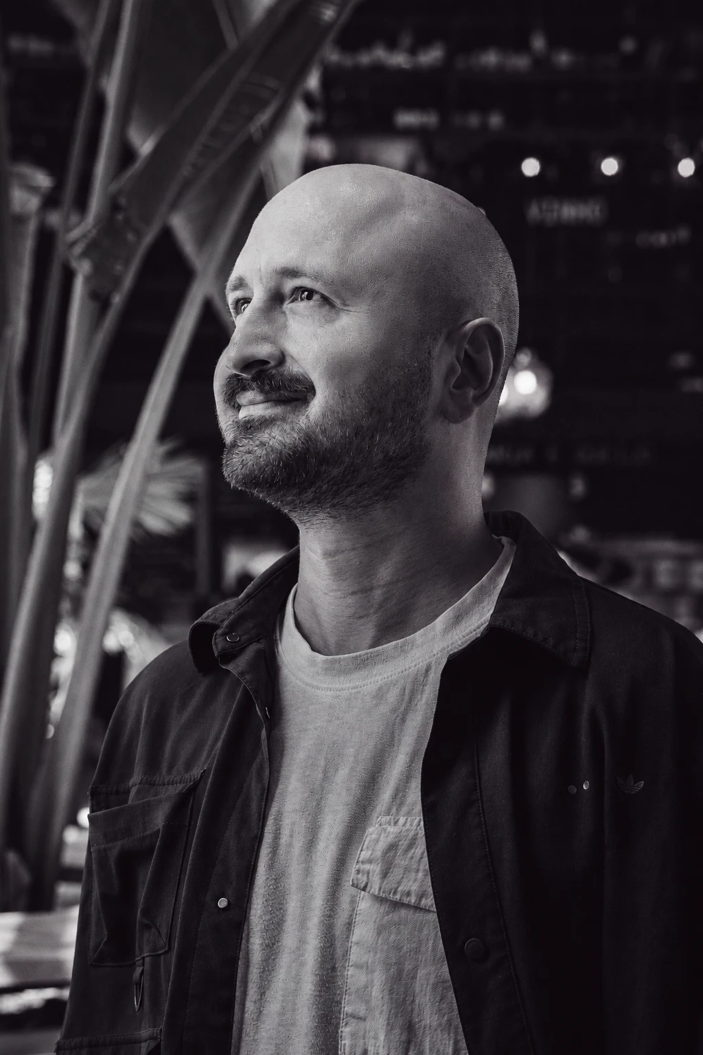 Black and white portrait of Temo K. Dolidze, founder of Hiveworx, smiling and looking up to the side, in a dark jacket and light T-shirt
